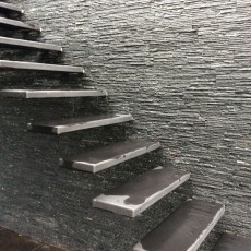 Wand van terrastrap met natuursteenstrips met zwarte tint