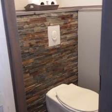 Wand van toilet met natuurruwe natuursteenstrips