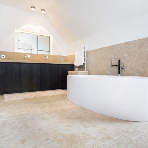 Badkamer met wit bad op kalksteen tegels