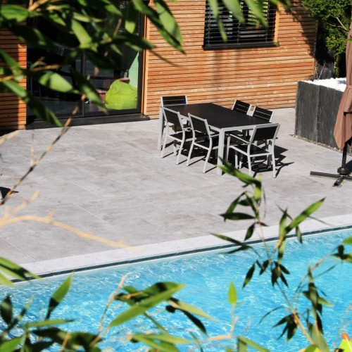 Zwart terrastafel naast zwembad op arduin tegels